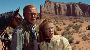 Movie still from “The Searchers” (1956), directed by John Ford – A man and a woman standing next to each other in the desert; Medium shot, Low angle