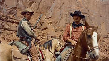 Movie still from “The Searchers” (1956), directed by John Ford – Two men sitting on horses in the desert; Medium shot, Low angle