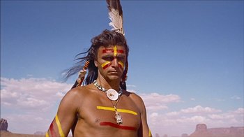 Movie still from “The Searchers” (1956), directed by John Ford – A native american man with painted face and feathers; Medium shot, Low angle
