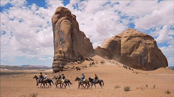 Movie still from “The Searchers” (1956), directed by John Ford – A group of people riding horses in the desert; Extreme Wide shot, Low angle