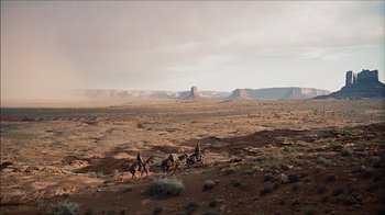Movie still from “The Searchers” (1956), directed by John Ford – A group of people riding horses across a desert; Extreme Wide shot, High angle