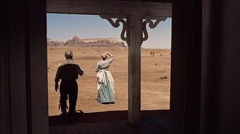 Movie still from “The Searchers” (1956), directed by John Ford – A man and a woman standing on a dirt field; Wide shot, Over the shoulder angle