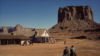 Movie still from “The Searchers” (1956), directed by John Ford – A group of people standing in front of an old house; Extreme Wide shot, Low angle