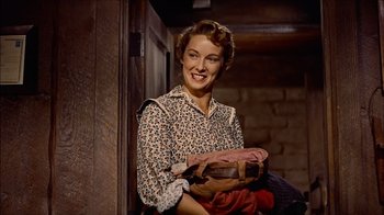 Movie still from “The Searchers” (1956), directed by John Ford – A woman holding a bag of clothes in her hands; Medium shot, Low angle
