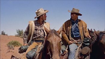 Movie still from “The Searchers” (1956), directed by John Ford – Two men sitting on a horse in a field; Medium shot, Low angle