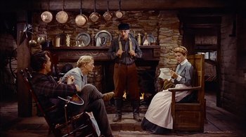 Movie still from “The Searchers” (1956), directed by John Ford – Three people sitting in front of a fire place; Wide shot, High angle