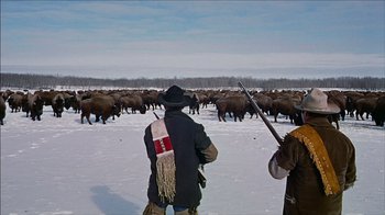 Movie still from “The Searchers” (1956), directed by John Ford – Two men are standing in the middle of a herd of buffalo; Wide shot, Low angle