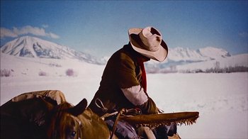 Movie still from “The Searchers” (1956), directed by John Ford – A man riding on the back of a brown horse; Medium shot, Low angle
