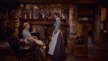 Movie still from “The Searchers” (1956), directed by John Ford – A woman in an old - fashioned dress standing in front of a man; Wide shot, Low angle