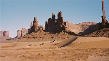 Movie still from “The Searchers” (1956), directed by John Ford – A group of people riding horses in the desert; Extreme Wide shot, Low angle