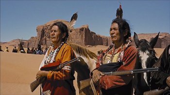 Movie still from “The Searchers” (1956), directed by John Ford – A couple of native americans standing next to each other; Medium shot, Low angle