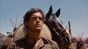 Movie still from “The Searchers” (1956), directed by John Ford – A man standing next to a horse in a field; Close Up shot, Low angle
