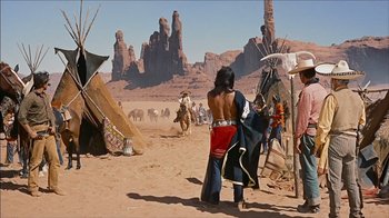Movie still from “The Searchers” (1956), directed by John Ford – A native american man standing in front of a teepee in the desert; Wide shot, Over the shoulder angle