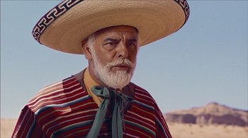 Movie still from “The Searchers” (1956), directed by John Ford – An old man wearing a sombrero and a striped shirt; Medium shot, Low angle