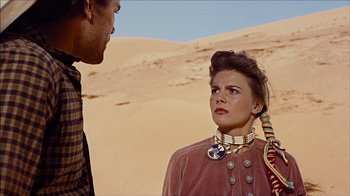 Movie still from “The Searchers” (1956), directed by John Ford – A man and a woman standing next to each other in the desert; Close Up shot, Over the shoulder angle