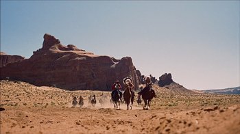 Movie still from “The Searchers” (1956), directed by John Ford – A group of people riding horses in the desert; Extreme Wide shot, Low angle