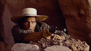 Movie still from “The Searchers” (1956), directed by John Ford – A man with a hat is holding a gun; Medium shot, Low angle
