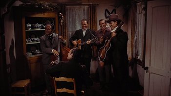 Movie still from “The Searchers” (1956), directed by John Ford – A group of men in suits and hats playing instruments; Wide shot, High angle
