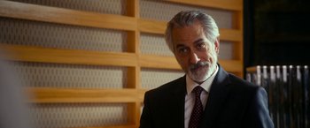 Movie still from “The Second Best Exotic Marigold Hotel” (2015), directed by John Madden – An older man in a black suit and a red tie; Close Up shot, Over the shoulder angle