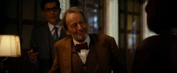 Movie still from “The Second Best Exotic Marigold Hotel” (2015), directed by John Madden – An older man wearing a suit and a bow tie; Medium shot, Over the shoulder angle