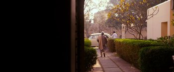 Movie still from “The Second Best Exotic Marigold Hotel” (2015), directed by John Madden – A man walking down a sidewalk next to a car; Wide shot, High angle