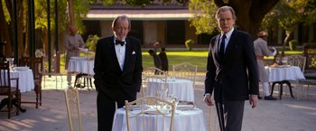 Movie still from “The Second Best Exotic Marigold Hotel” (2015), directed by John Madden – A man and a woman standing next to each other at a table; Medium shot, Over the shoulder angle