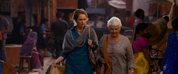 Movie still from “The Second Best Exotic Marigold Hotel” (2015), directed by John Madden – Two women walking down a street holding shopping bags; Medium shot, Over the shoulder angle