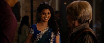 Movie still from “The Second Best Exotic Marigold Hotel” (2015), directed by John Madden – A woman in a blue and gold sari smiling; Medium shot, Over the shoulder angle