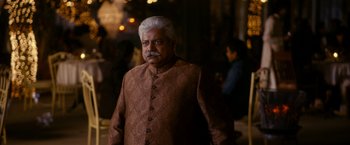 Movie still from “The Second Best Exotic Marigold Hotel” (2015), directed by John Madden – An older man with a white beard wearing a brown jacket; Medium shot, Over the shoulder angle