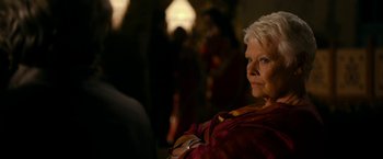 Movie still from “The Second Best Exotic Marigold Hotel” (2015), directed by John Madden – An older woman with white blonde hair is looking at the camera; Close Up shot, Over the shoulder angle