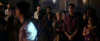 Movie still from “The Second Best Exotic Marigold Hotel” (2015), directed by John Madden – A group of people standing in front of a building; Medium shot, Over the shoulder angle