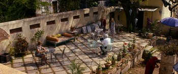 Movie still from “The Second Best Exotic Marigold Hotel” (2015), directed by John Madden – A group of people standing around a patio area; Wide shot, High angle