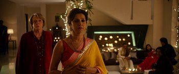 Movie still from “The Second Best Exotic Marigold Hotel” (2015), directed by John Madden – A woman in a yellow and pink sari standing in a room; Medium shot, Over the shoulder angle