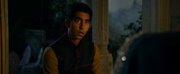 Movie still from “The Second Best Exotic Marigold Hotel” (2015), directed by John Madden – A man in a black and yellow jacket looking at the camera; Close Up shot, Over the shoulder angle