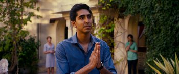 Movie still from “The Second Best Exotic Marigold Hotel” (2015), directed by John Madden – A man in a blue dress shirt is praying outside; Medium shot, Over the shoulder angle