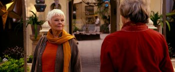 Movie still from “The Second Best Exotic Marigold Hotel” (2015), directed by John Madden – An older woman standing in a courtyard with a young man; Medium shot, Over the shoulder angle