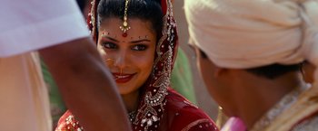 Movie still from “The Second Best Exotic Marigold Hotel” (2015), directed by John Madden – A woman in a red dress and a white headpiece; Close Up shot, Over the shoulder angle
