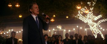 Movie still from “The Second Best Exotic Marigold Hotel” (2015), directed by John Madden – An older man in a suit is holding a microphone; Medium shot, Low angle