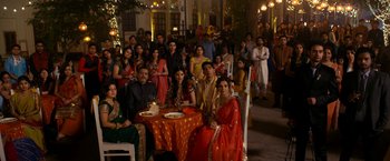 Movie still from “The Second Best Exotic Marigold Hotel” (2015), directed by John Madden – A group of people sitting around a table with food on it; Wide shot, High angle