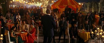 Movie still from “The Second Best Exotic Marigold Hotel” (2015), directed by John Madden – A group of people standing in a room with lights; Wide shot, Over the shoulder angle
