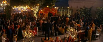 Movie still from “The Second Best Exotic Marigold Hotel” (2015), directed by John Madden – A group of people sitting in a courtyard at night; Extreme Wide shot, High angle