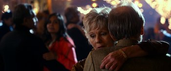 Movie still from “The Second Best Exotic Marigold Hotel” (2015), directed by John Madden – An older woman is hugging a younger man in a crowd; Close Up shot, Over the shoulder angle
