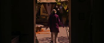 Movie still from “The Second Best Exotic Marigold Hotel” (2015), directed by John Madden – An older woman in a purple coat walking through a doorway; Wide shot, High angle