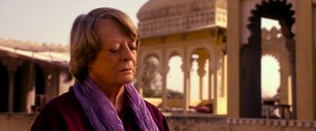 Movie still from “The Second Best Exotic Marigold Hotel” (2015), directed by John Madden – An older woman wearing a purple scarf looking down at the ground; Close Up shot, Over the shoulder angle