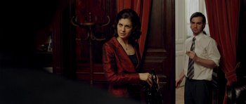 Movie still from “The Secret in Their Eyes” (2009), directed by Juan José Campanella – A woman in a red jacket holding a black purse; Medium shot, Over the shoulder angle
