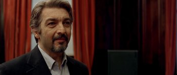 Movie still from “The Secret in Their Eyes” (2009), directed by Juan José Campanella – A person wearing a suit and beard; Close Up shot, Over the shoulder angle