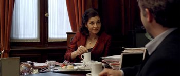 Movie still from “The Secret in Their Eyes” (2009), directed by Juan José Campanella – A woman sitting at a table with a cup of coffee; Medium shot, Over the shoulder angle
