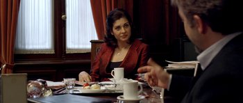 Movie still from “The Secret in Their Eyes” (2009), directed by Juan José Campanella – A woman sitting at a table with a plate in front of her; Medium shot, Over the shoulder angle