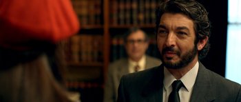 Movie still from “The Secret in Their Eyes” (2009), directed by Juan José Campanella – A man in a suit and tie in front of a book case; Close Up shot, Over the shoulder angle