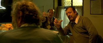 Movie still from “The Secret in Their Eyes” (2009), directed by Juan José Campanella – A group of men sitting at a table with drinks; Medium shot, Low angle
